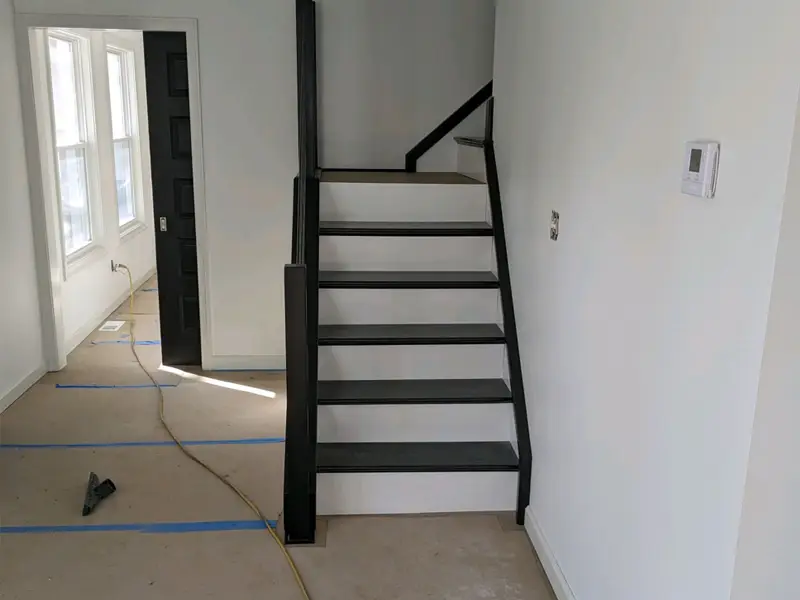 Black and white staircase in a room under renovation with taped floor protection. certified restoration experts